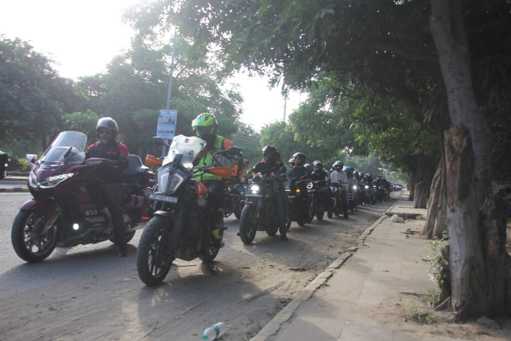 
A mixed group of motorcycles, including a Honda Goldwing and a KTM Adventure, with riders from the DBBR biker group on a group ride along a shady, tree-lined road.