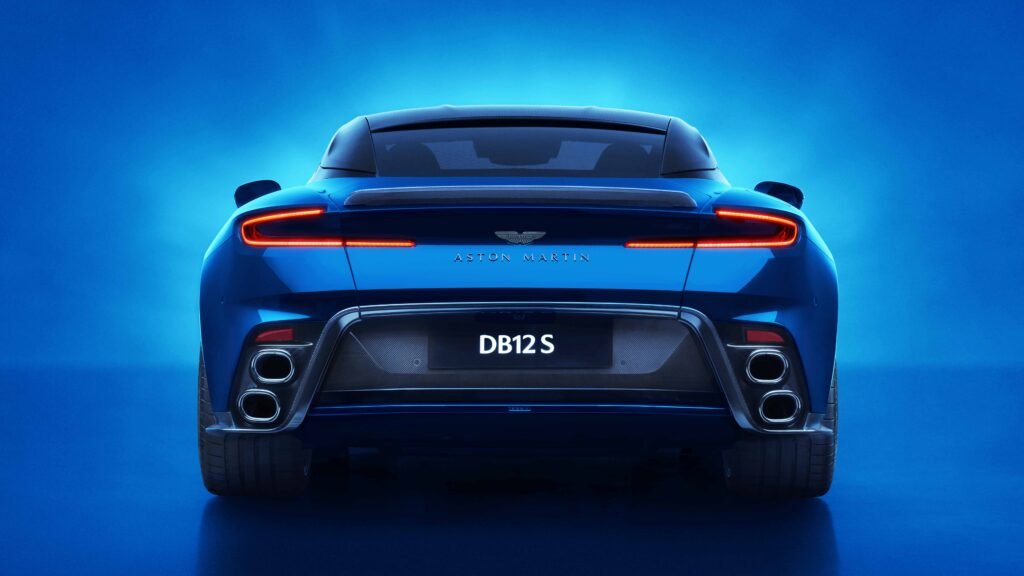 
Rear view of the blue Aston Martin DB12 S, showcasing its full-width LED taillight, aggressive diffuser, quad exhaust system, and a license plate that reads "DB12 S".