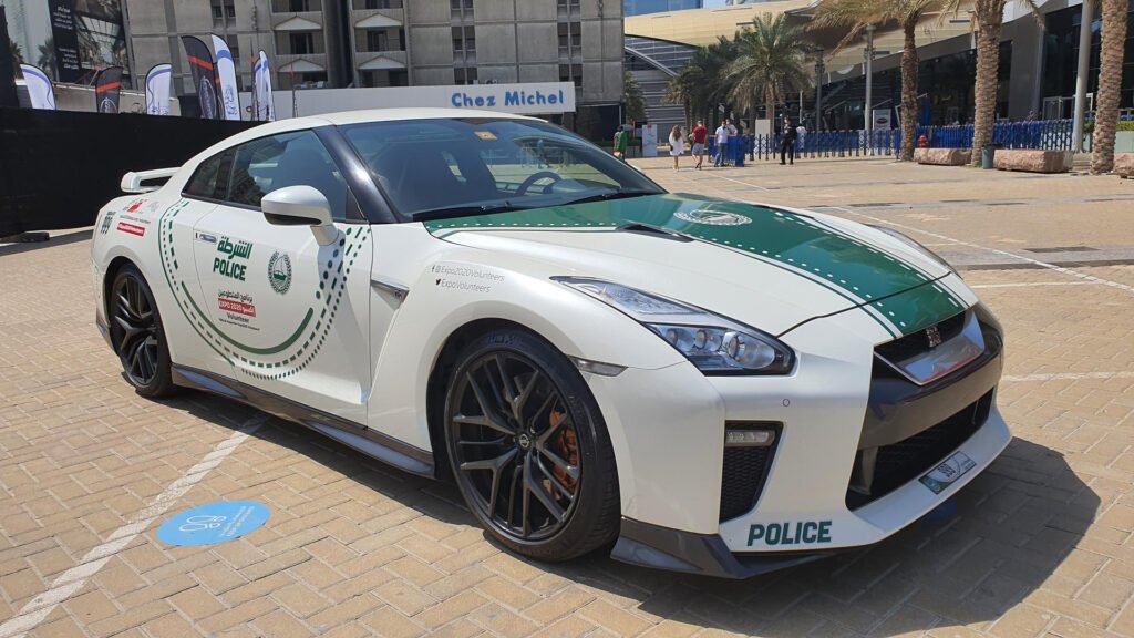 Dubai Police cars featuring a Nissan GT-R supercar in official white and green police livery parked in a public area